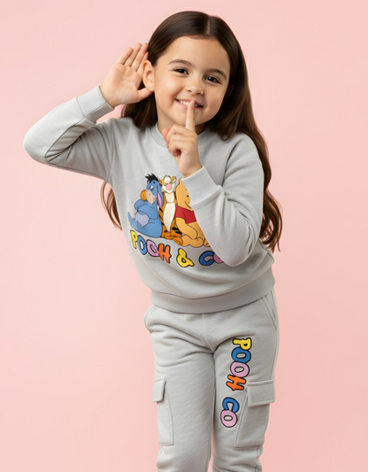 Child wearing a gray outfit with cartoon character design on a pink background